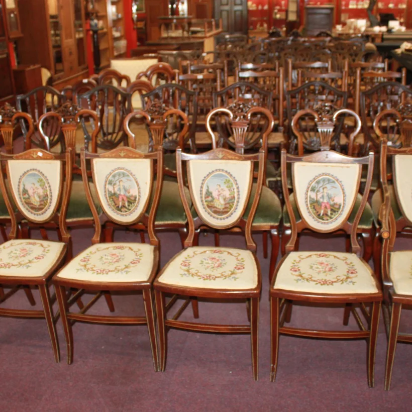 Rows of Edwardian inlaid chairs with needlework seats at Shelbys in Armley