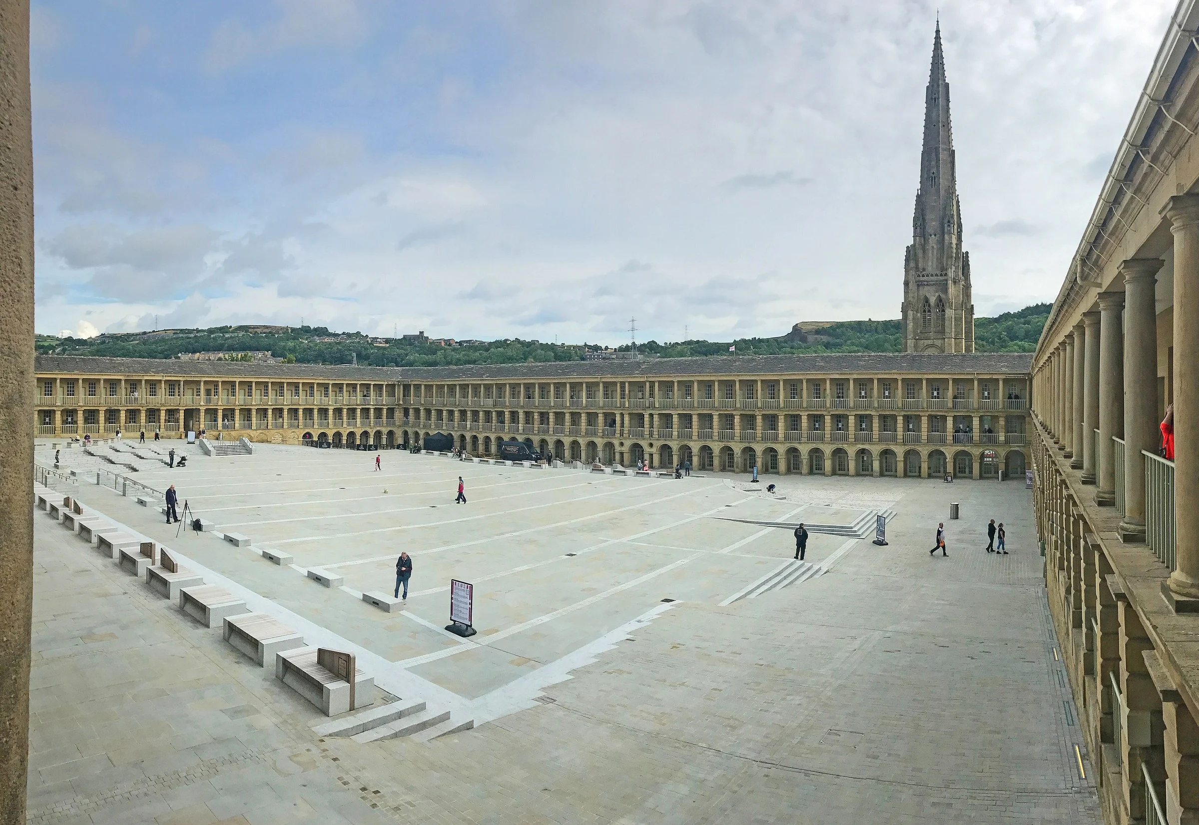 Piece Hall courtyard panorama with a church spire and a hill behind