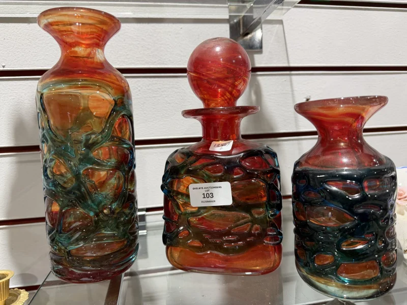Three Mdina glass strapped vessels on a shelf