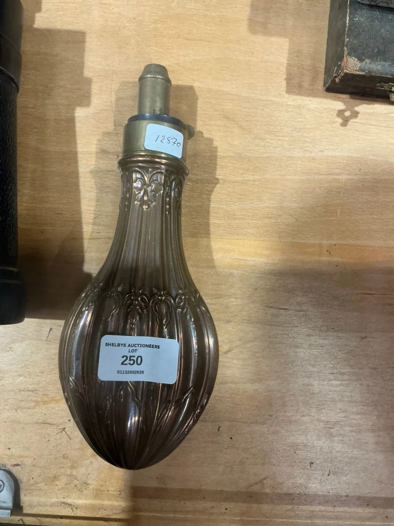 Embossed 19th-century copper and brass powder flask with its lot ticket